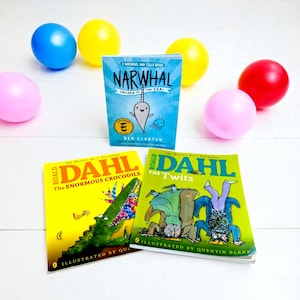 以下が含まれることがあります： 子供向けの本とカラフルな風船のコレクション。「Narwhal: Unicorn of the Sea!」と、ロアルド・ダールの「The Enormous Crocodile」と「The Twits」の2冊の本が含まれています。風船は青、黄色、ピンク、赤です。