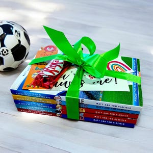 Op de afbeelding: Een stapel van vijf boeken, ingepakt in een groen lint met een chocolade reep en een kaart met de tekst "Have a awesome!" De boeken gaan over voetbalhelden en zijn van Matt en Tom Oldfield.