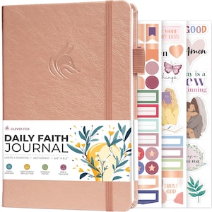 May include: A rose gold Daily Faith Journal with a fox logo embossed on the cover, an elastic closure, and a pen loop. The journal includes a paper band with floral illustrations and text, plus three sheets of decorative stickers with faith-themed designs.