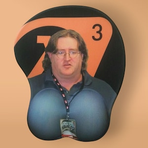 May include: A black and orange mouse mat with the number "73" printed on it. A man with glasses is pictured on the mouse mat.