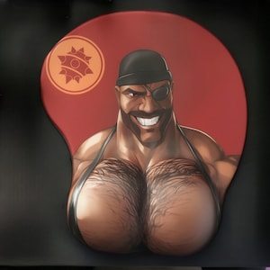 Op de afbeelding: Rode ergonomische muismat met een cartoonillustratie van een gespierde man met een zwarte hoed, ooglapje en een brede glimlach. De muismat heeft een polssteun en een cirkelvormig logo in de linkerbovenhoek.
