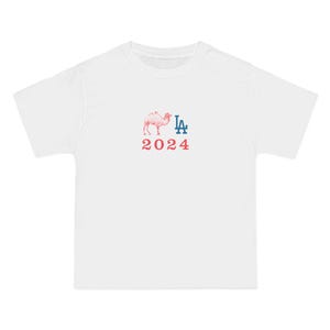 May include: White t-shirt with a pink camel graphic and the text "LA 2024" in red and blue.