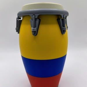 May include: A colorful conga drum with a yellow, blue, and red design. The drum has a gray rim and hardware. The drum is a musical instrument, perfect for percussion.