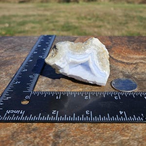 Puede incluir: Un trozo de &aacute;gata de encaje azul con bandas azules claras y blancas, junto a una regla y una moneda. El &aacute;gata tiene una textura natural rugosa y mide aproximadamente 7.6 cm de largo.