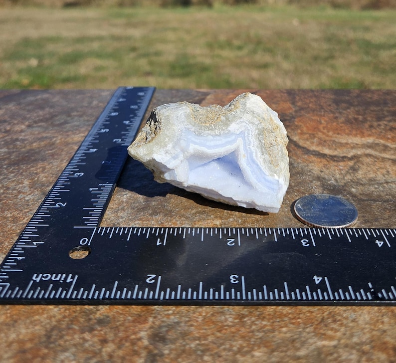 Puede incluir: Un trozo de &aacute;gata de encaje azul con bandas azules claras y blancas, junto a una regla y una moneda. El &aacute;gata tiene una textura natural rugosa y mide aproximadamente 7.6 cm de largo.