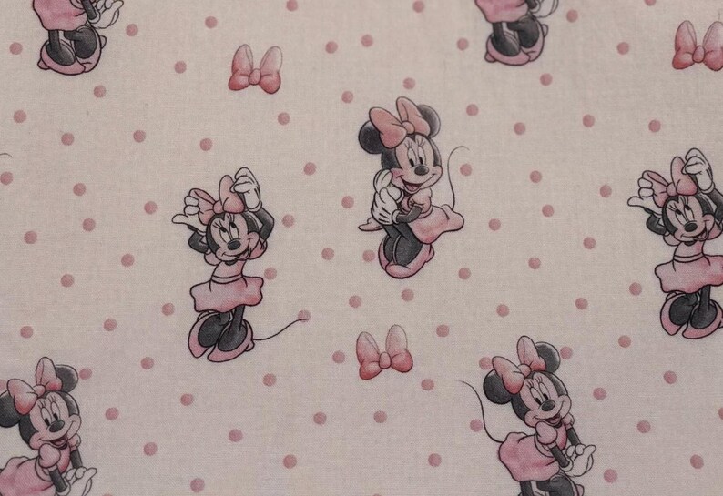 May include: A repeating pattern featuring Minnie Mouse in various poses, wearing a pink dress and bow. The background is a light pink with evenly spaced pink polka dots. The overall design is whimsical and playful.