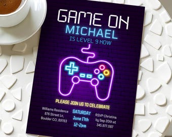 May include: A purple and blue neon sign with a video game controller and the text "GAME ON MICHAEL IS LEVEL 9 NOW". The sign is on a brick wall background. The text below the sign says "PLEASE JOIN US TO CELEBRATE" and includes details for a party.