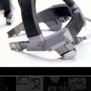 Puede incluir: Primer plano de un auricular gris y negro con un diseño acanalado. El auricular está diseñado para ajustarse a la cabeza y tiene una correa flexible y ajustable.