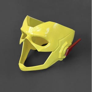 May include: A yellow plastic mask with a red lightning bolt detail. The mask is designed to resemble a superhero's mask.