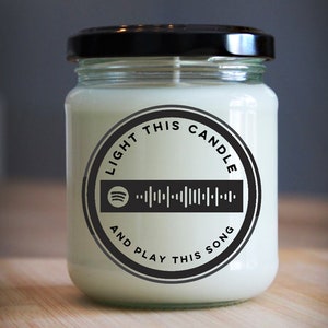 May include: A white candle with a black label that says "Light this candle and play this song" with a Spotify logo and a barcode.