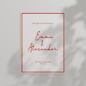 Può includere: Un annuncio di matrimonio bianco con un bordo rosso. Il testo recita "Benvenuti al matrimonio di Emma & Alexander, Seattle, Washington 09.20.25".