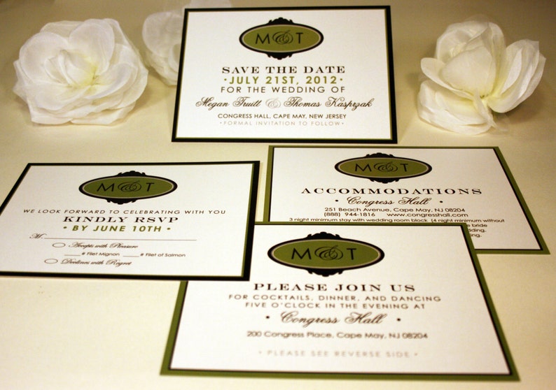 May include: Four ivory wedding invitation cards with black and green borders. The cards feature a monogram with the initials "M&T" in a green oval with a black border. The text on the cards includes the date "July 21st, 2012", the names "Megan Fruitt & Thomas Kasprzak", and the location "Congress Hall, Cape May, New Jersey".