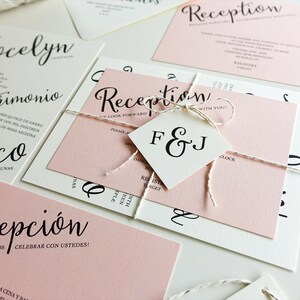 Peut inclure: Ensemble d'invitations de mariage avec du papier rose et blanc. L'invitation comporte le texte "Jocelyn et Francisco" en &eacute;criture cursive noire. La carte de r&eacute;ception comporte le texte "Reception" en &eacute;criture cursive noire et le texte "&iexcl;ESPERAMOS CELEBRAR CON USTEDES!" en texte noir. La carte RSVP comporte le texte "F&J" en texte noir.