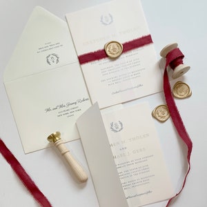 Hochzeitseinladung in Goldfolie mit weinrotem Band und goldenem Wachssiegel mit Monogramm-Wappen