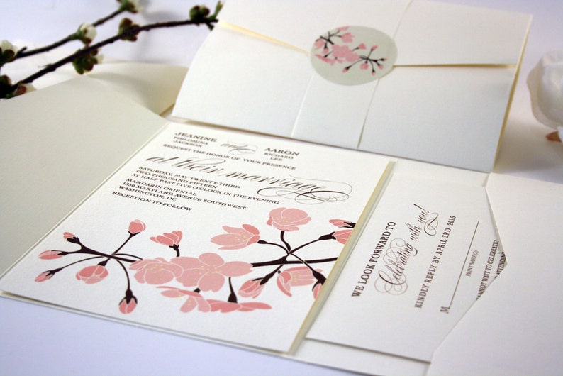 K&ouml;nnte beinhalten: Eine gefaltete Hochzeitseinladung mit einem rosa-braunen Blumendesign. Die Einladung enth&auml;lt die Namen "Jeanine" und "Aaron" sowie den Text "at their marriage". Die RSVP-Karte enth&auml;lt den Text "We look forward to celebrating with you!" und "Kindly reply by April 3rd, 2015".