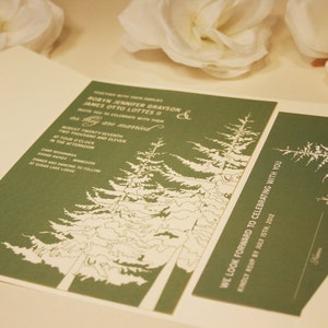 Op de afbeelding: Een groene huwelijksuitnodiging met witte tekst en een ontwerp van dennenbomen. De uitnodiging luidt "Robin Jennifer Grayson & James Otto Lottes II" en "We kijken ernaar uit om met u te vieren. Graag uw aanwezigheid bevestigen voor 15 juli 2012."