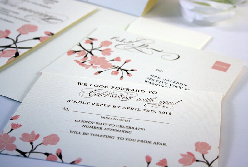K&ouml;nnte beinhalten: Eine wei&szlig;e RSVP-Karte mit rosa Kirschbl&uuml;ten-Illustrationen. Der Text lautet "We look forward to celebrating with you!" und "Kindly reply by April 3rd, 2015".