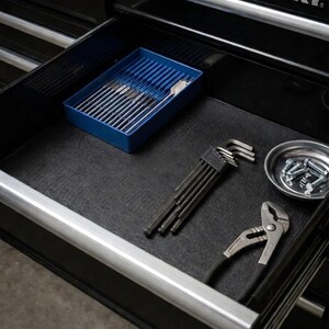 May include: Open drawer of a black Husky tool chest. Inside, a blue tray holds various tools, including a set of Allen wrenches, pliers, and a small dish with screws. The drawer has a black liner and a silver handle.
