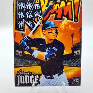 May include: Baseball card featuring Aaron Judge of the New York Yankees. The card has a vibrant orange and black background with the word "BAM!" in large letters. The card also includes the text "ROOKIE RC CARD".