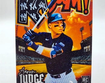 May include: Baseball card featuring Aaron Judge of the New York Yankees. The card has a vibrant orange and black background with the word "BAM!" in large letters. The card also includes the text "ROOKIE RC CARD".