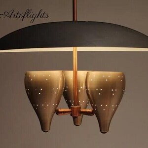 May include: A mid-century modern chandelier with a black canopy and three gold-toned, perforated, cone-shaped shades.
