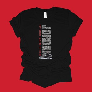 Puede incluir: Camiseta negra con un gr&aacute;fico blanco y gris de una zapatilla Jordan y el texto "JORDAN MY SHOE GAME IS FIRE!"