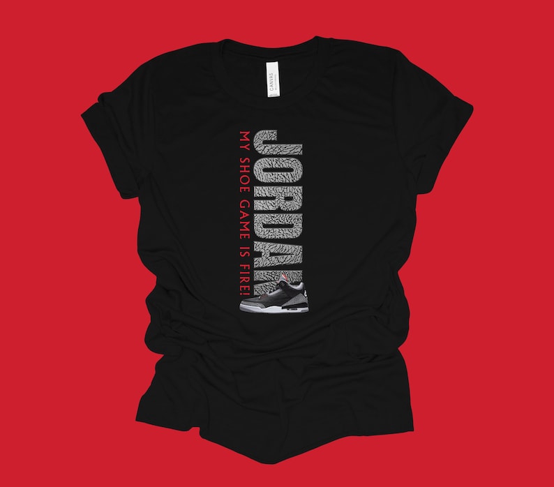 Puede incluir: Camiseta negra con un gr&aacute;fico blanco y gris de una zapatilla Jordan y el texto "JORDAN MY SHOE GAME IS FIRE!"