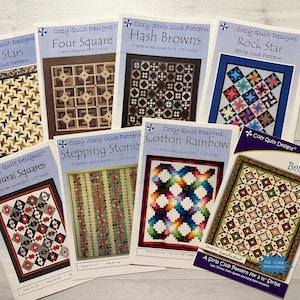 May include: A collection of ten quilt patterns featuring various designs, including "All Stars", "Four Square", "Hash Browns", "Rock Star", "Samurai Squares", "Stepping Stone", "Cotton Rainbow", and "Bellagio". Each pattern is printed on a white sheet of paper with a black and white border.