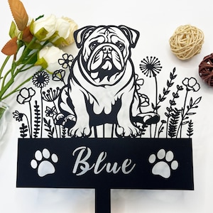 May include: Black metal garden stake featuring a silhouette of a bulldog with flowers and foliage. The stake has a black sign with the name "Blue" and two paw prints.
