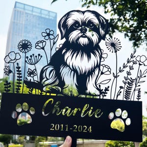 May include: Black metal silhouette of a dog with flowers and the name Charlie and the dates 2011-2024.