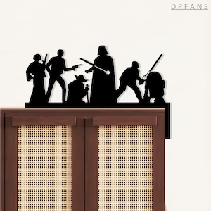 May include: Black silhouette of Star Wars characters, including Darth Vader, Yoda, and R2-D2, displayed on top of a wooden cabinet. The figures are arranged in a dynamic pose, suggesting action and adventure. The design is a decorative accent for fans of the franchise.