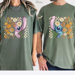 Puede incluir: Dos camisetas verde musgo con un dise&ntilde;o dividido de un personaje de dibujos animados con una flor de margarita. El dise&ntilde;o incluye un patr&oacute;n de cuadros y un arreglo floral en tonos naranja, amarillo y blanco.
