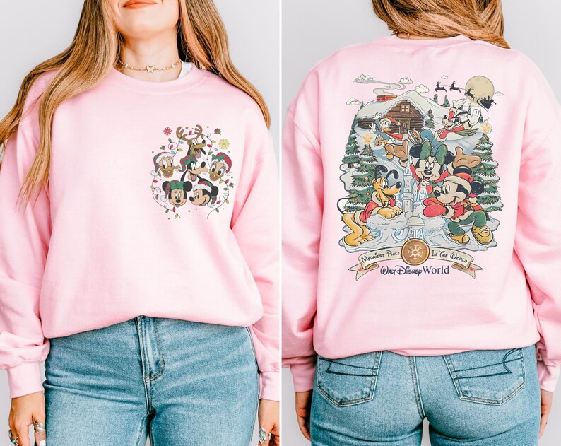 May include: Pink sweatshirt with a Christmas-themed design featuring Mickey Mouse and friends. The front of the sweatshirt has a smaller design with Mickey Mouse and friends. The back of the sweatshirt has a larger design with Mickey Mouse and friends in a winter wonderland scene. The sweatshirt has the text "Wondrous Place To See The Magic" and "Walt Disney World" on the back.