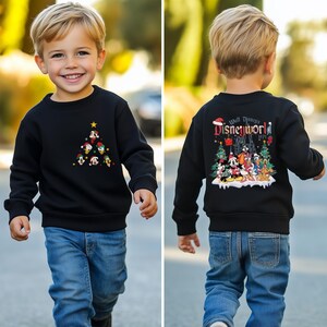Pode incluir: Uma camisa de frio preta com um design de &aacute;rvore de Natal com personagens da Disney. A parte de tr&aacute;s da camisa de frio tem um design que diz "Walt Disney's Disneyworld 1971" com Mickey Mouse e outros personagens da Disney.