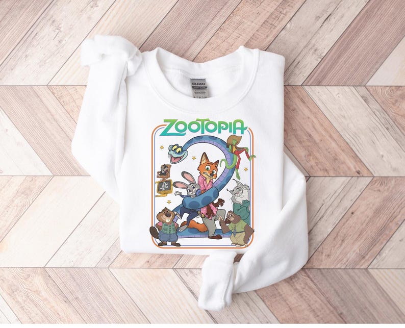Pu&ograve; includere: Felpa girocollo bianca con una grafica colorata del film d'animazione "Zootropolis". Il design include la parola "Zootopia" in verde, insieme a personaggi dei cartoni animati come una volpe, un coniglio e altri animali. La felpa &egrave; realizzata in materiale morbido.