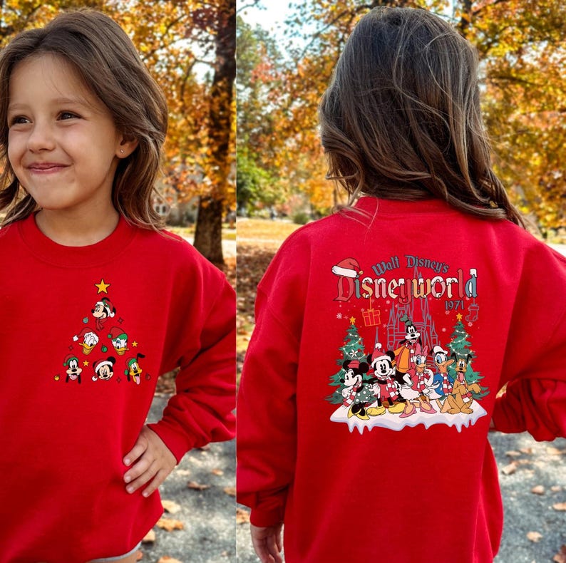 Pode incluir: Camisola vermelha de Natal com um design de Mickey Mouse e seus amigos. A frente da camisola apresenta uma &aacute;rvore de Natal com ornamentos de Mickey Mouse e seus amigos. As costas da camisola apresentam uma cena de Mickey Mouse e seus amigos em frente ao Castelo da Cinderela com o texto "Walt Disney's Disneyworld 1971".
