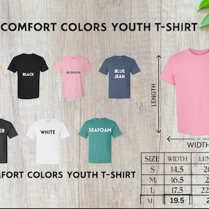 Puede incluir: Exhibici&oacute;n de camisetas Comfort Colors para j&oacute;venes en varios colores, incluyendo mantequilla, negro, flor, azul vaquero, pimienta, blanco y espuma de mar. Se muestra una camiseta rosa con indicadores de largo y ancho. Tabla de tallas incluida.