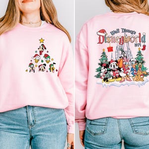 Pode incluir: Camisola cor-de-rosa com um design de &aacute;rvore de Natal com o Mickey Mouse e os seus amigos na frente e um design "Walt Disney's Disneyworld 1971" nas costas.
