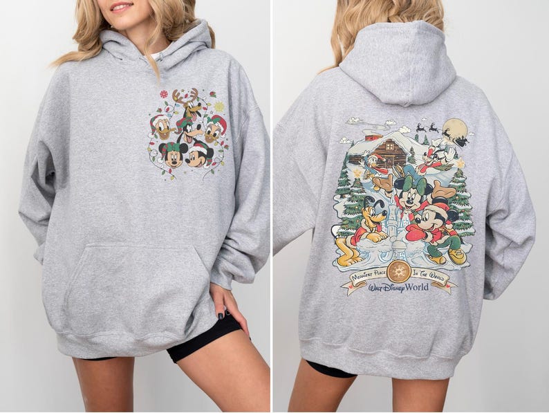 May include: Gray hooded sweatshirt with a Christmas-themed Mickey Mouse and friends print on the front and a winter scene with Mickey Mouse and friends on the back. The back print includes the text "Memories Made In The Magic" and "Walt Disney World".