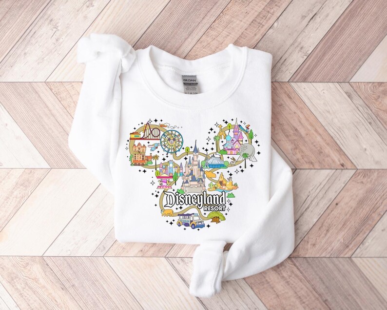 May include: White crew neck sweatshirt with a colourful Disneyland Resort graphic in the shape of Mickey Mouse's head. The design includes various park attractions and the words "Disneyland Resort".
