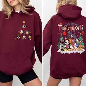 Pode incluir: Moletom bord&ocirc; com um design de &aacute;rvore de Natal com Mickey Mouse e outros personagens da Disney. A parte de tr&aacute;s do moletom tem o texto "Walt Disney's Disneyworld 1971".