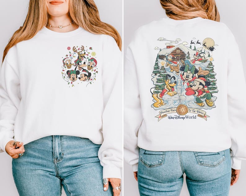 May include: White sweatshirt with a Christmas-themed Mickey Mouse design on the front and a larger design on the back. The back design features Mickey Mouse, Minnie Mouse, Pluto, and Goofy in a winter scene with a cabin and the text "Remember Place In The Magic" and "Walt Disney World".