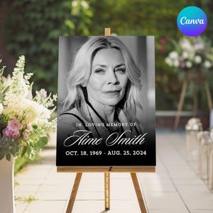 May include: A black and white memorial sign on a wooden easel. The sign features a portrait of a woman and the text "IN LOVING MEMORY OF Aime Smith OCT. 18, 1969 - AUG. 25, 2024". The Canva logo is in the upper right corner.