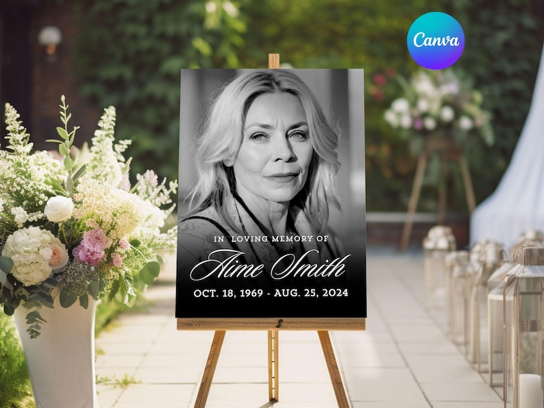 May include: A black and white memorial sign on a wooden easel. The sign features a portrait of a woman and the text "IN LOVING MEMORY OF Aime Smith OCT. 18, 1969 - AUG. 25, 2024". The Canva logo is in the upper right corner.