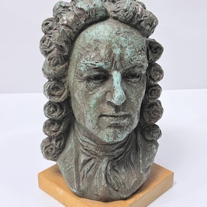 Op de afbeelding: Een bronzen buste van een man met krullend haar en een serieuze uitdrukking. De sculptuur heeft een groen patina en is gemonteerd op een kleine, vierkante houten sokkel. De buste is een klassieke weergave van een historische figuur.