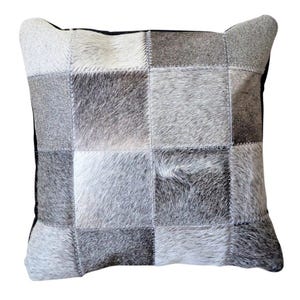 Może przedstawiać: Szara i biała poduszka w patchworku z czarną obwódką. Poduszka jest wykonana ze skóry krowiej i ma miękką, puszystą fakturę.