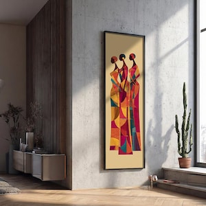 May include: A framed art print depicting three figures in long dresses. The artwork uses a geometric style and a warm colour palette of red, orange, yellow, and teal. The print is displayed against a neutral background, creating a striking visual contrast.