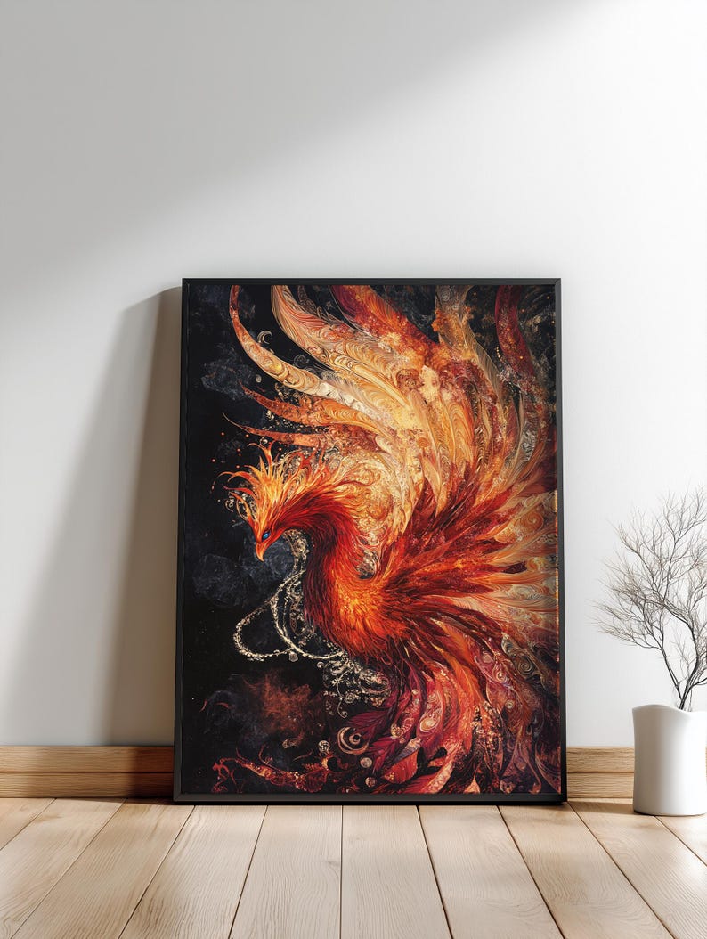 May include: Framed artwork featuring a vibrant phoenix in shades of red, orange, and gold. The mythical bird is depicted with detailed feathers and a dynamic pose against a dark background. The artwork is displayed in a black frame, leaning against a white wall.