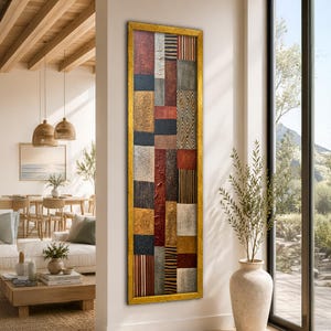 May include: A tall, rectangular wall art piece framed in gold, featuring a vertical collage of textured panels in shades of red, black, gold, silver, and white, with various geometric patterns including stripes, chevrons, and solid blocks.