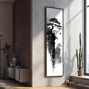 May include: Black and white framed artwork featuring a minimalist landscape with a tree and a red sun. The artwork is displayed on a concrete wall, adding a touch of nature-inspired decor to the room.